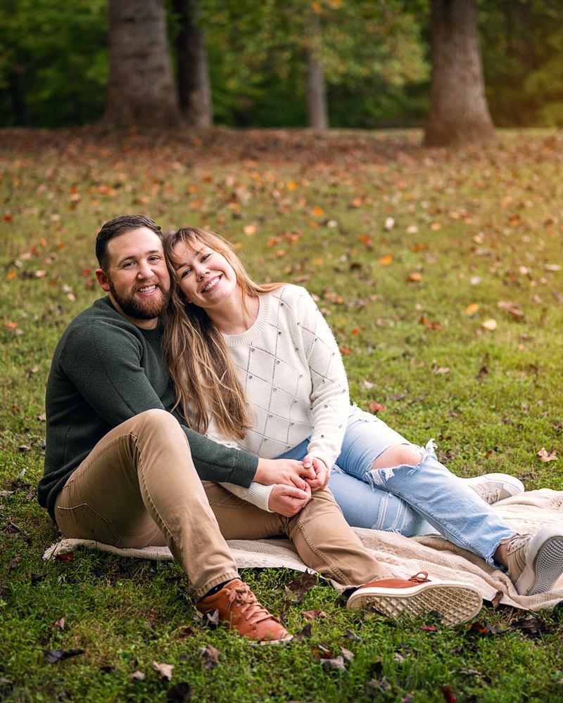 Ian Shannon and his partner Marjorie sitting together on a blanket in a Cary, North Carolina park on an autumn afternoon
